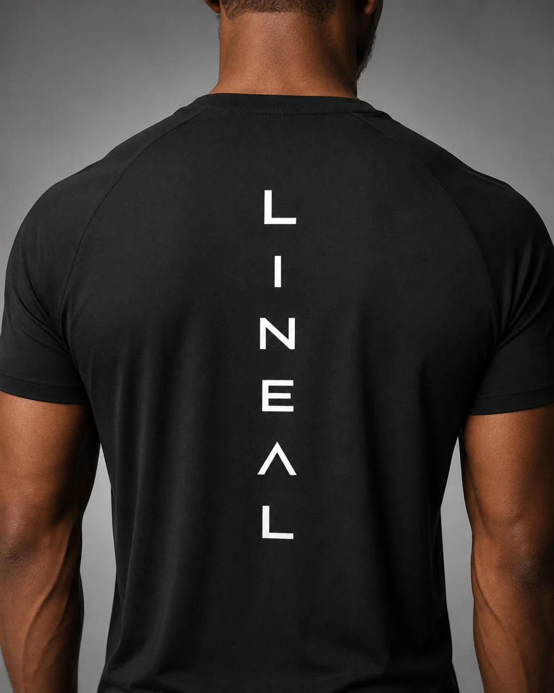 Vertical LINEAL spinal wordmark on the back of a black performance tee